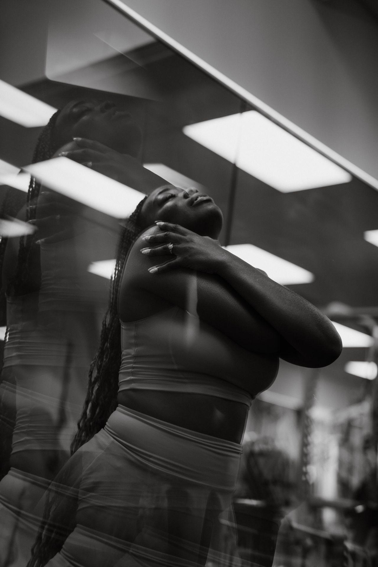 Black and white photo of a woman posing gracefully with her eyes closed, reflected in glass.